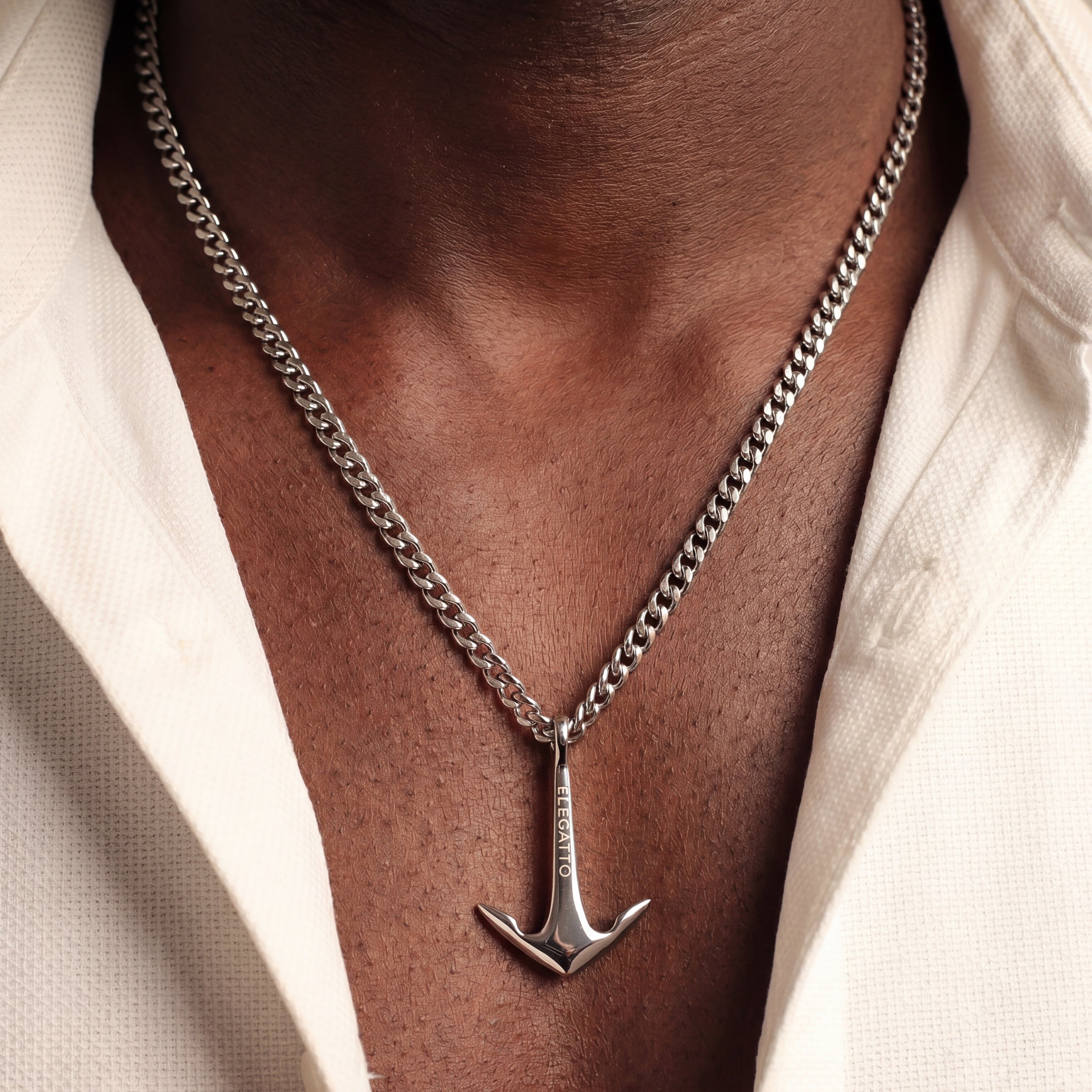 Silver anchor necklace on a person wearing a light-colored shirt