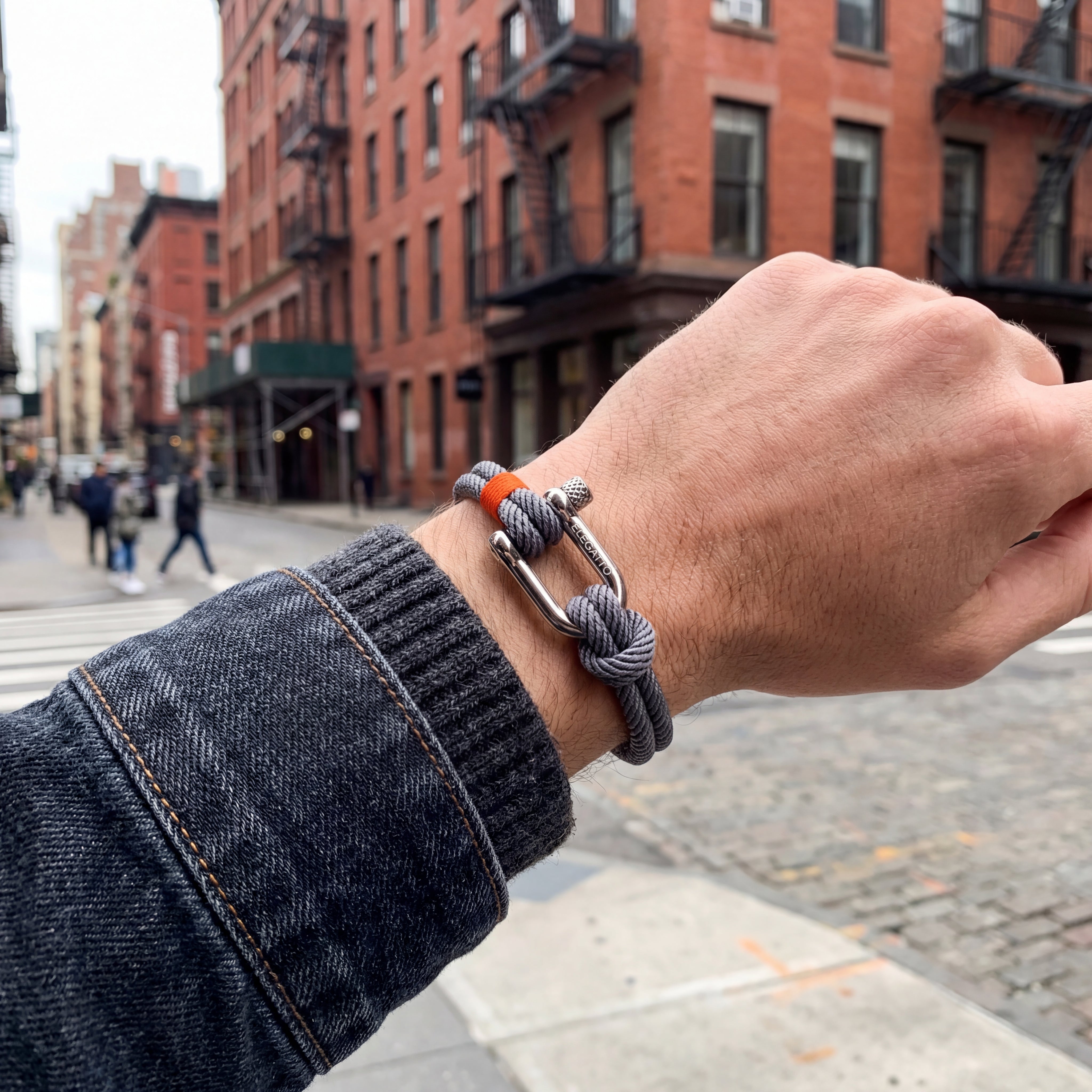 Hand wearing a bracelet with a city street background