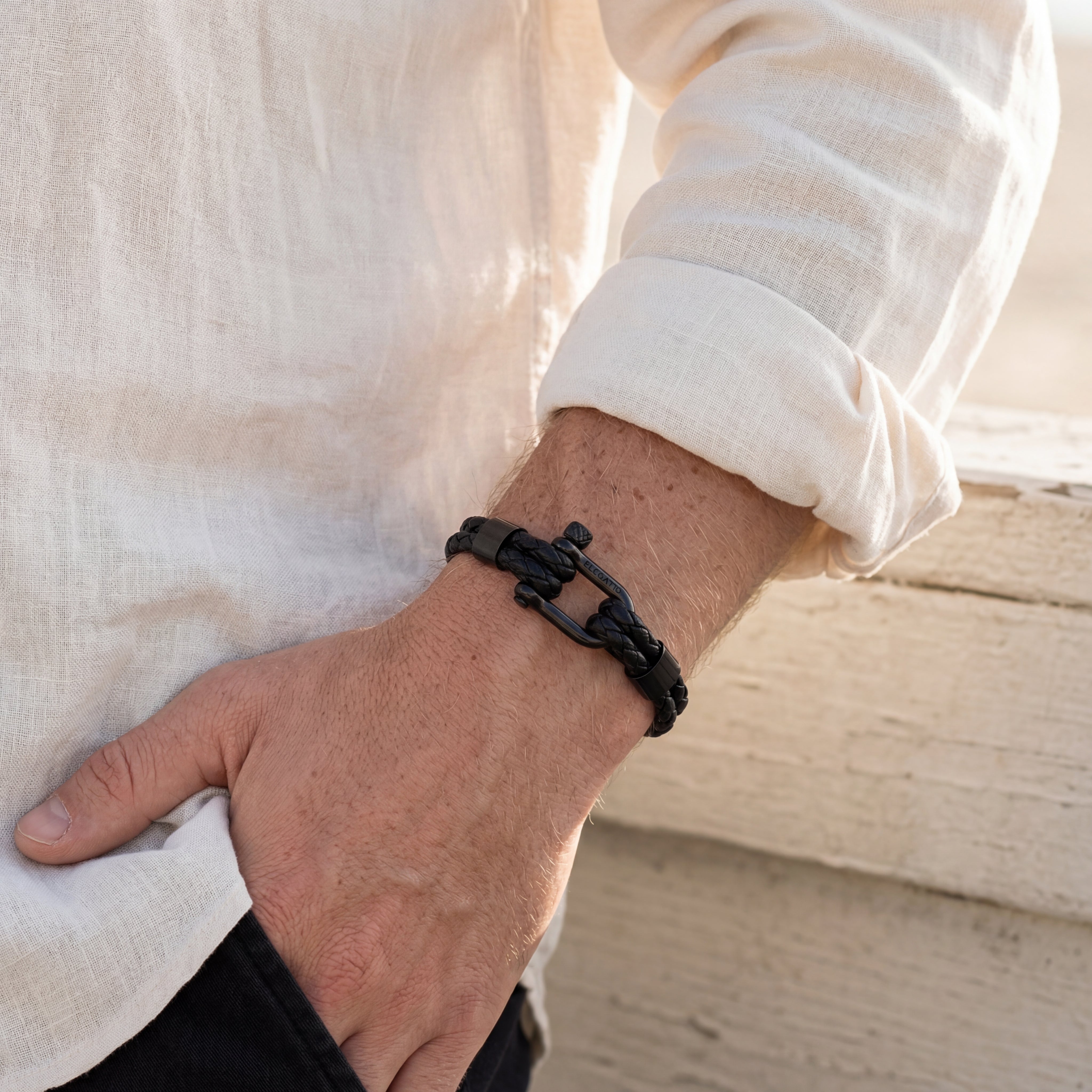 Person wearing a black braided bracelet on a neutral background